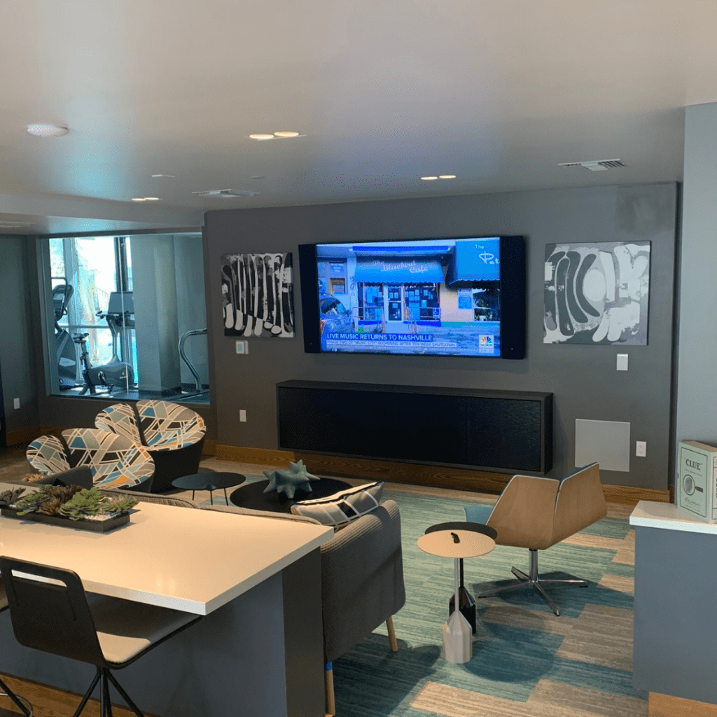 A living area with a huge television and a set of sofas with abstract design